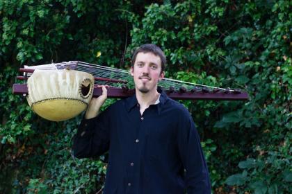 Image of artist, Sean Gaskell posing with his kora harp instrument.