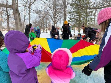 group of kids and parents playing with parachute