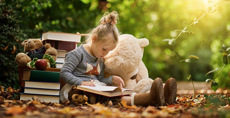 Girl reading to stuffed bear